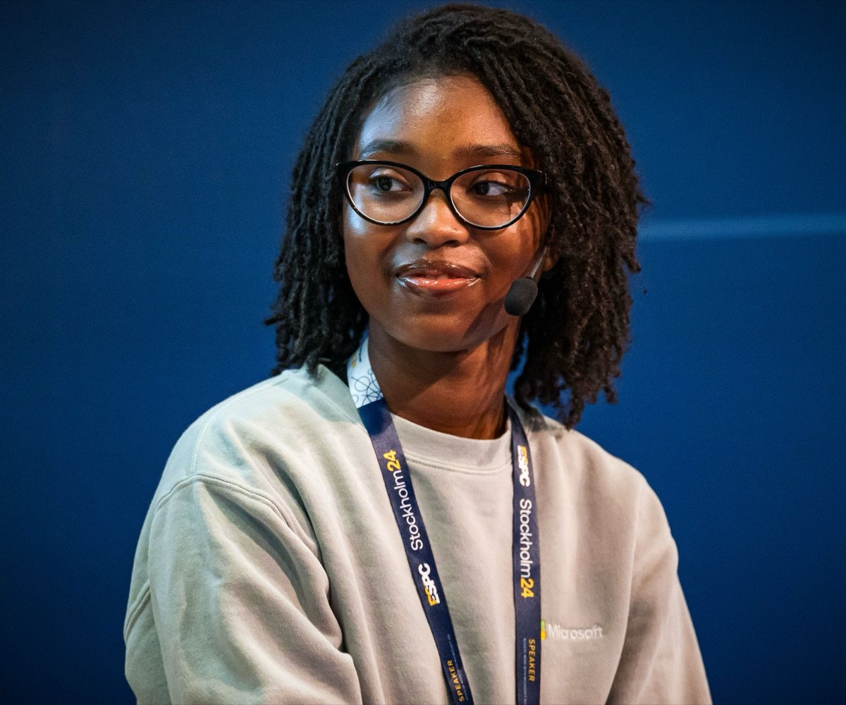 Gabrielle Williams on stage with a headset microphone and an ESPC Stockholm 2024 speaker lanyard